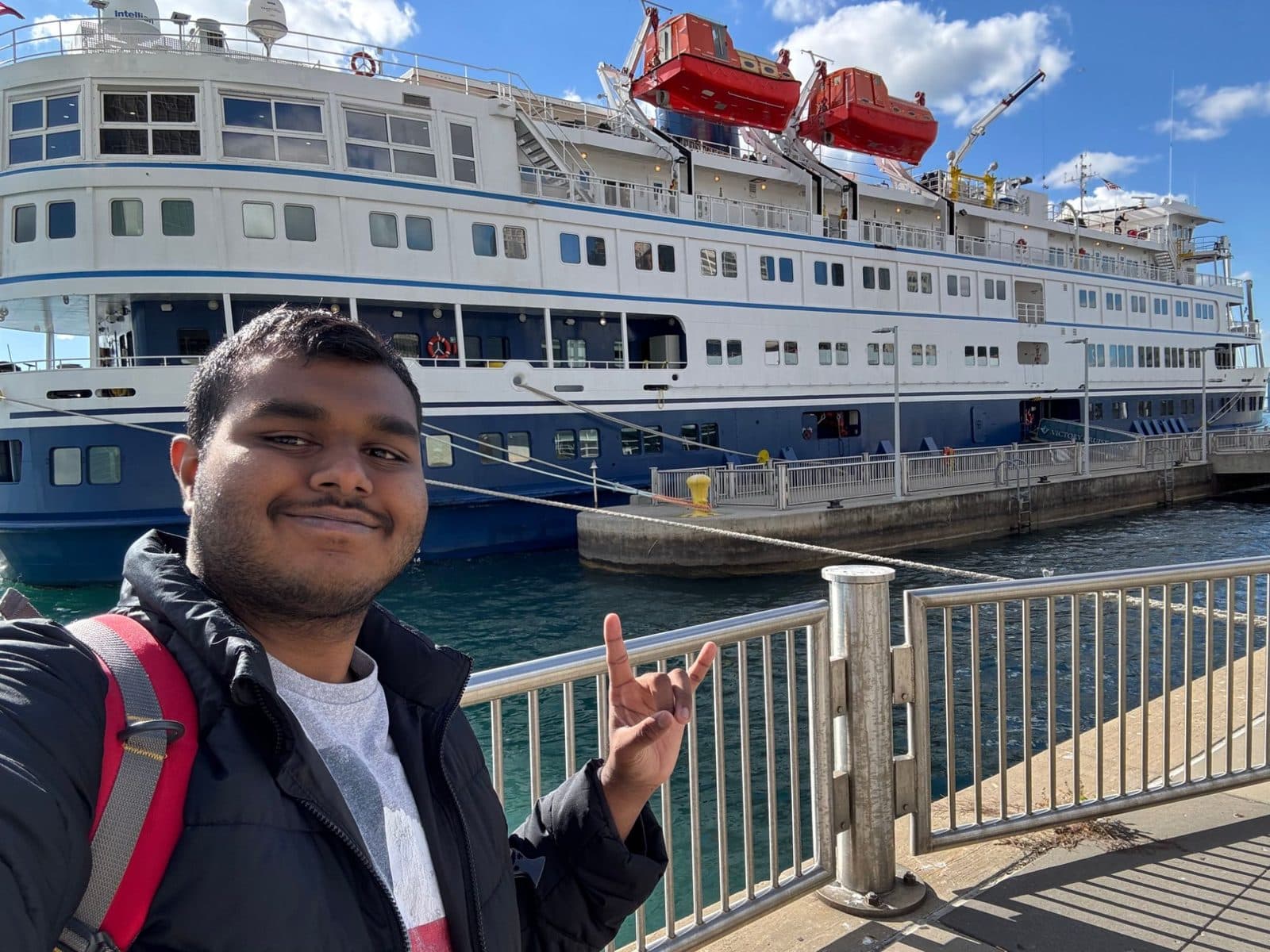 Vishanth selfie with the horns sign in front of a docked cruise ship