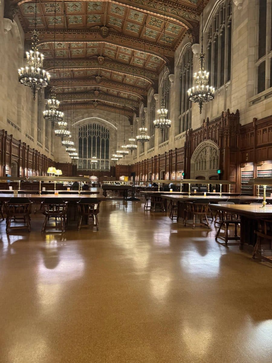 Chandeliers and a carved wood ceiling above long reading tables