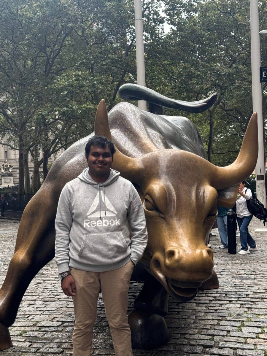 Vishanth standing next to the Charging Bull statue