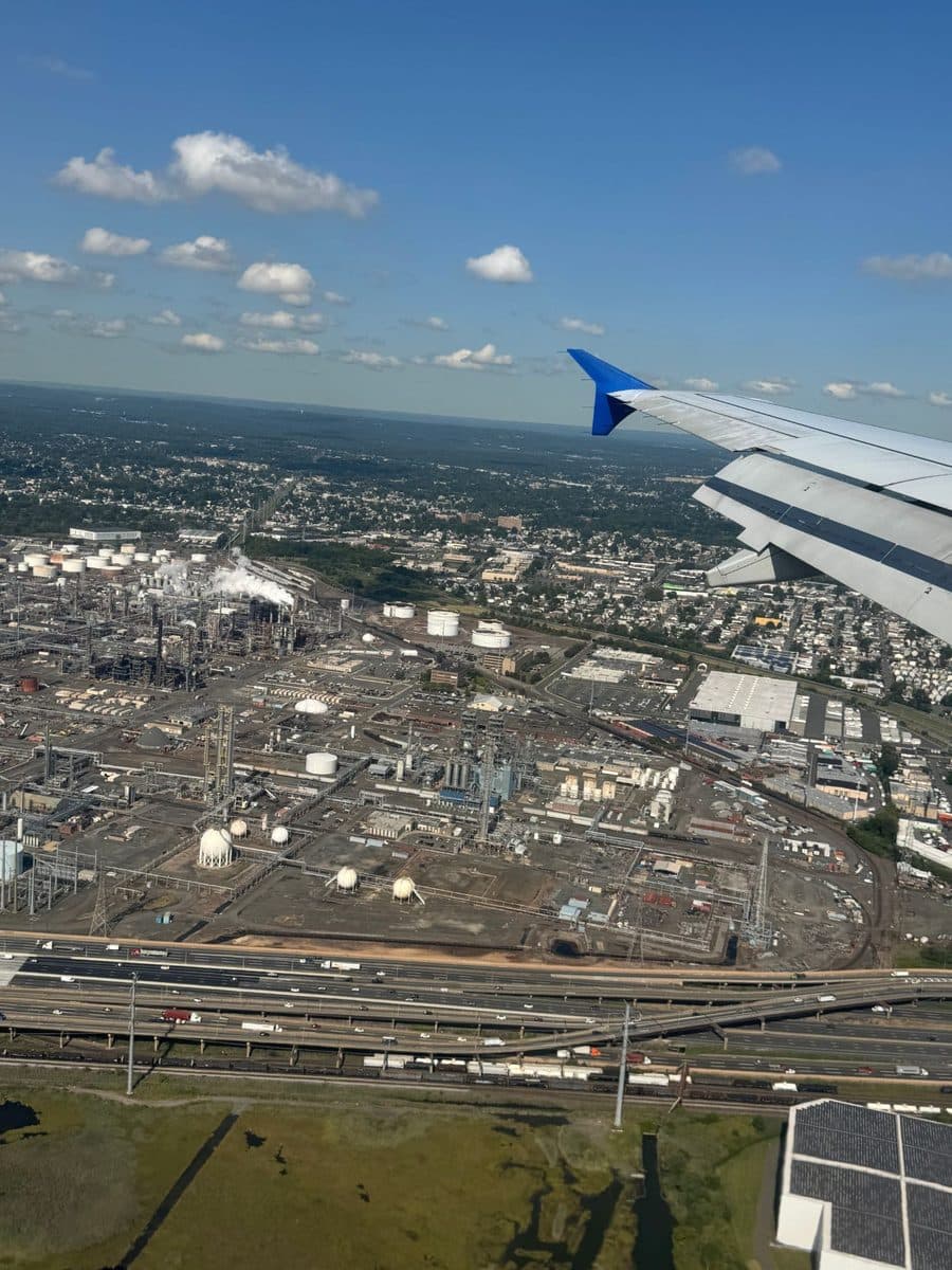 Plane wing over New Jersey refineries and highways on approach