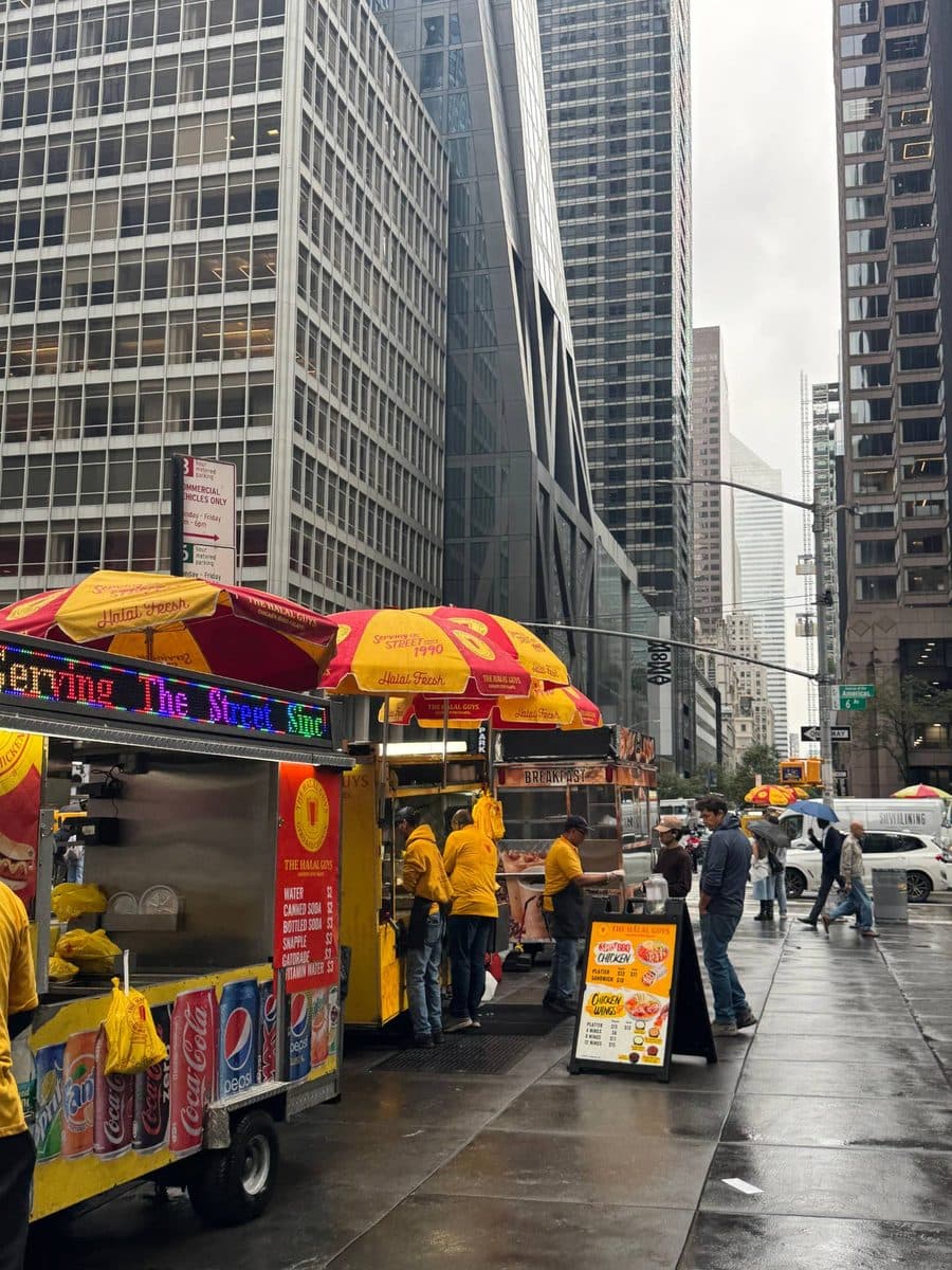 Halal Guys food carts on a wet Midtown sidewalk
