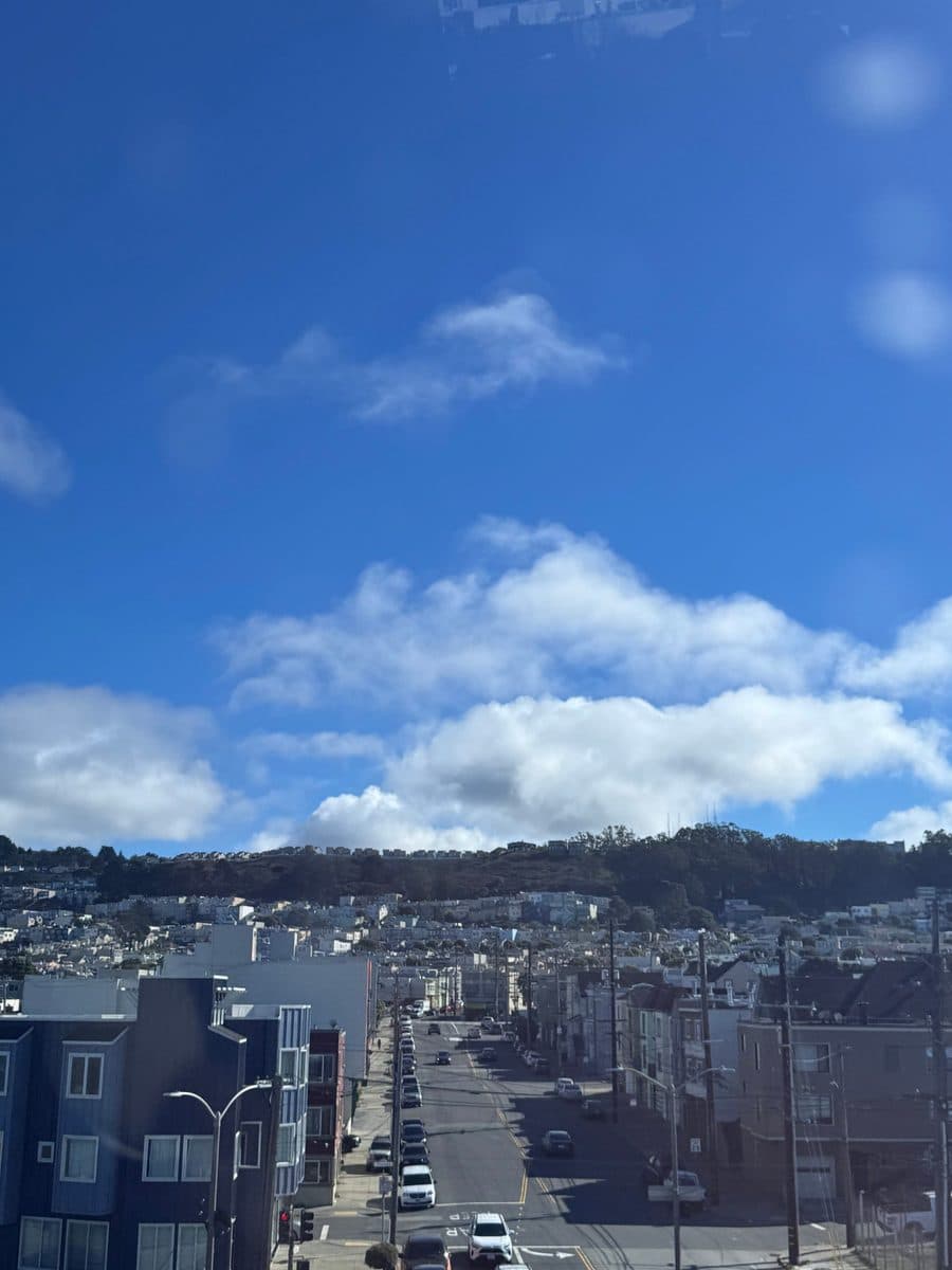 San Francisco street running toward green hills under a blue sky